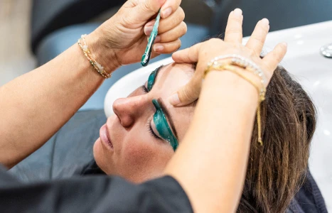 Eine Frau mit blauen Augen und Augenbrauen auf denen eine Mascarabürste aufgetragen wird
